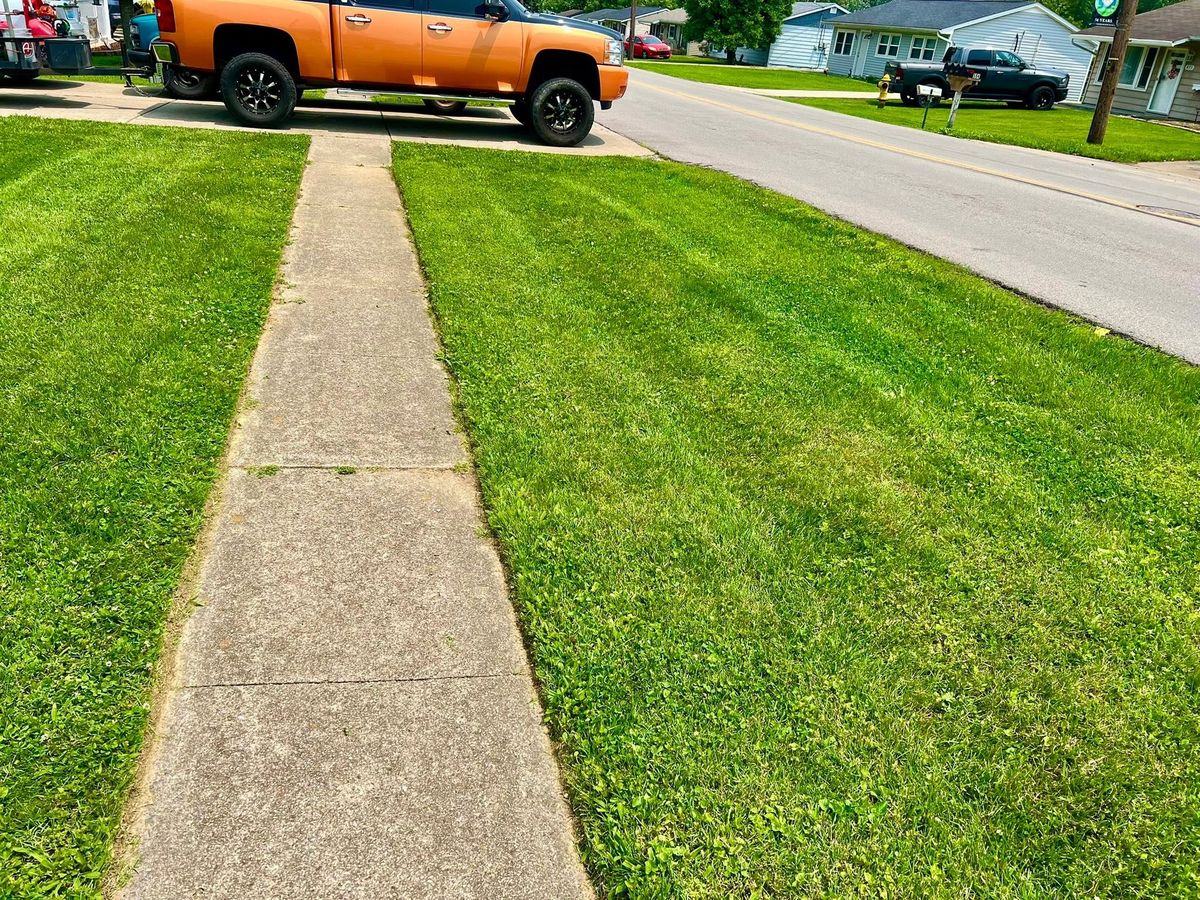A sidewalk with a razor-clean cut edge on both sides, the orange truck up the street